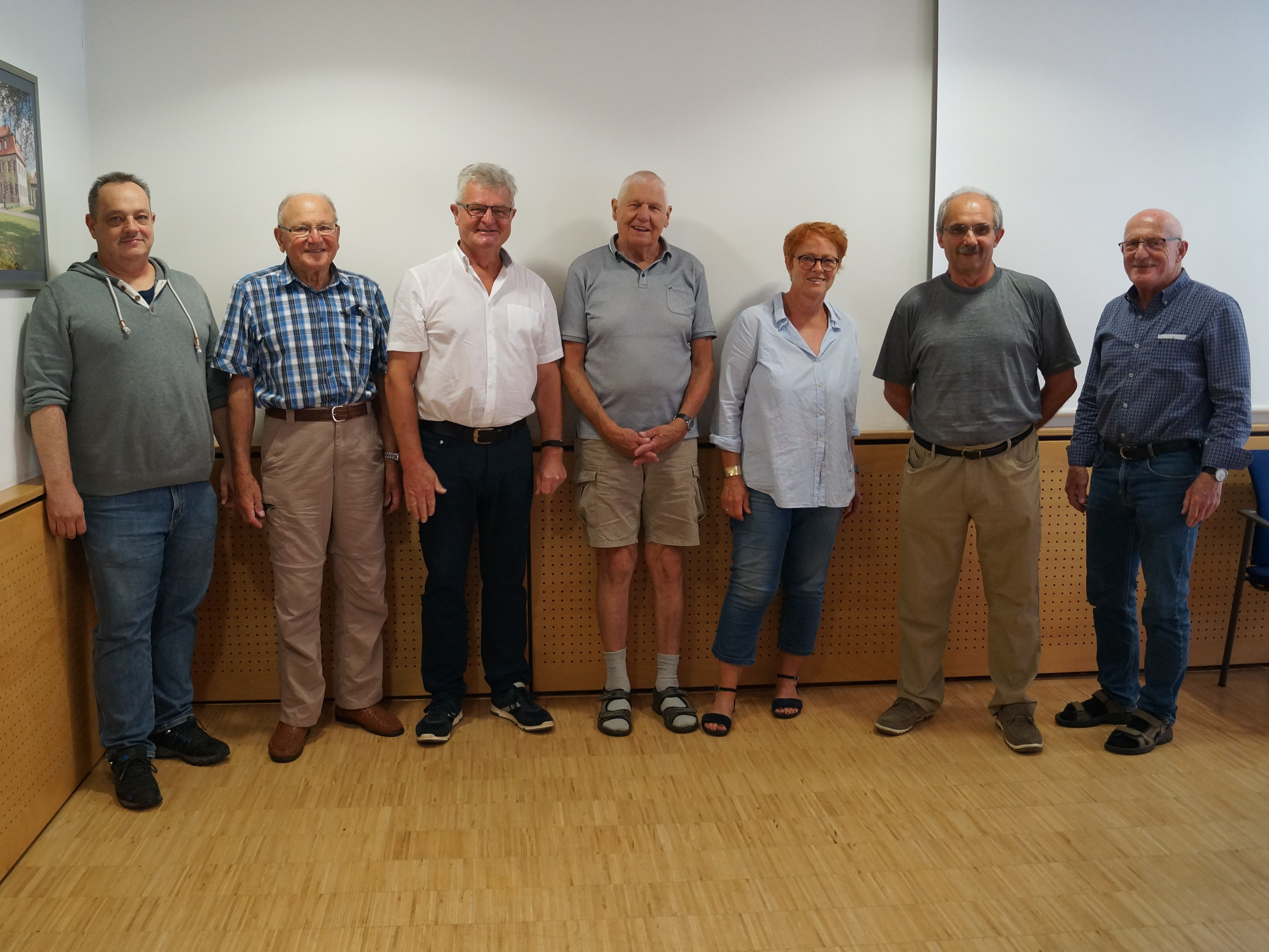 Sechs ältere Herren, darunter Oskar Fürst, stehen nebeneinander und blicken in die Kamera. Zwischen ihnen steht die Dritte Bürgermeisterin Rita Bogner.